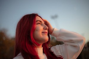 Girl with fire engine red hair standing outside at dusk 